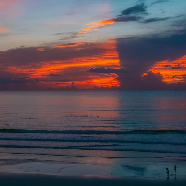 Silhouette of a person meditating against a sunrise with vibrant colors.